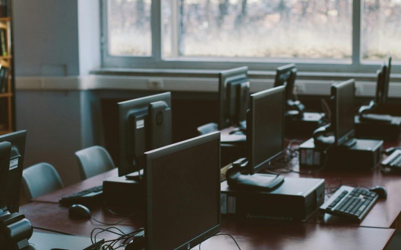 Spacious computer lab with rows of monitors and keyboards in a sunlit room.